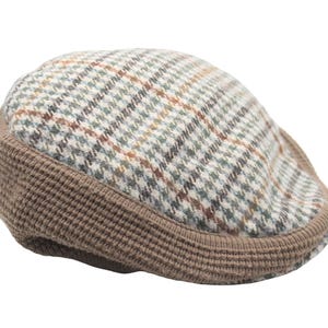 Puede incluir: Gorra plana de tweed con una banda acanalada marrón y un estampado de cuadros en tonos beige, verde y marrón. El sombrero es de estilo clásico, adecuado para diversas ocasiones.
