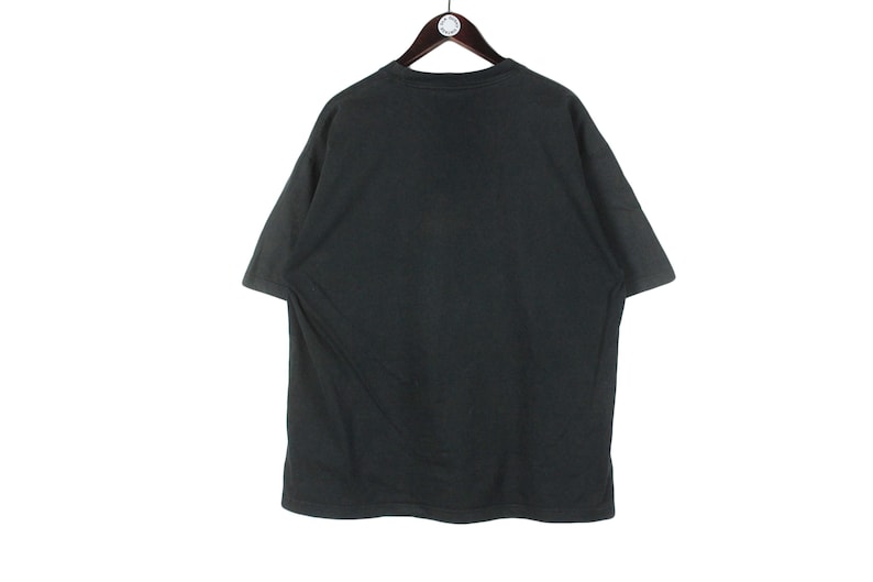 May include: A black short-sleeved t-shirt hanging on a wooden hanger. The shirt is plain and appears to be made of a soft fabric. The background is white.