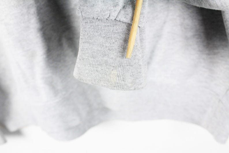 Puede incluir: Primer plano del pu&ntilde;o de tela gris de una sudadera. La tela es suave y texturizada.