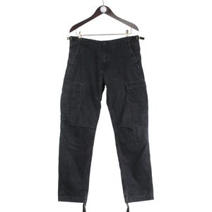 Puede incluir: Pantalones cargo negros colgados de una percha de madera. Los pantalones tienen m&uacute;ltiples bolsillos, cierre de bot&oacute;n y cremallera, y cordones en los tobillos. Los pantalones est&aacute;n hechos de una tela duradera.