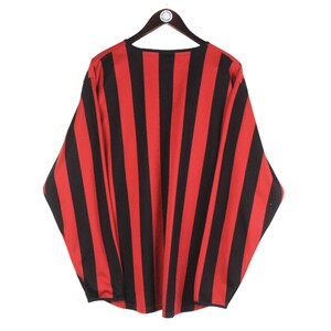 Puede incluir: Una camisa de manga larga con rayas verticales rojas y negras, colgada de una percha de madera. El patr&oacute;n de la camisa es consistente en toda la prenda, creando una declaraci&oacute;n visual audaz. La tela parece ser ligera.