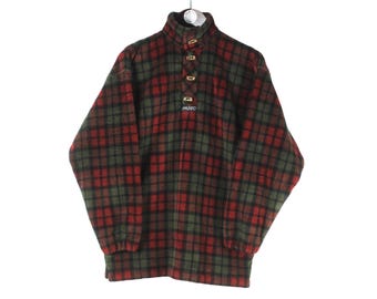 May include: Red and green plaid fleece pullover with a high neck and button closure. The pullover has a logo on the front.
