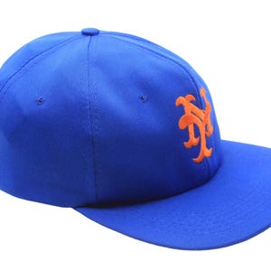 May include: A royal blue baseball cap with a flat brim. The cap features an orange embroidered logo on the side. The hat is made of a durable fabric and has a structured fit.