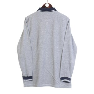 May include: A gray long-sleeved shirt with a navy blue collar and cuffs. The shirt is hanging on a wooden hanger against a white background. The cuffs and collar have a navy blue trim.