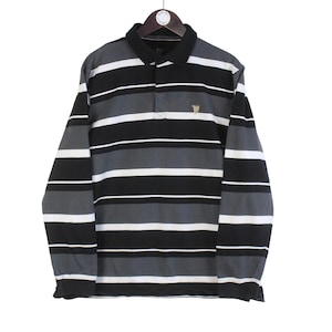 May include: Long-sleeved polo shirt with horizontal stripes in black, white, and gray. The shirt has a black collar and a small emblem on the chest. It is hanging on a wooden hanger.