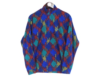May include: A vintage sweater with a high neckline, featuring a repeating diamond pattern. The pattern incorporates blue, red, teal, and gold colors. The sweater is displayed on a hanger against a white background.