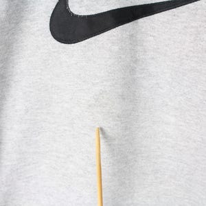 Puede incluir: Una sudadera gris con un logotipo Nike swoosh negro.