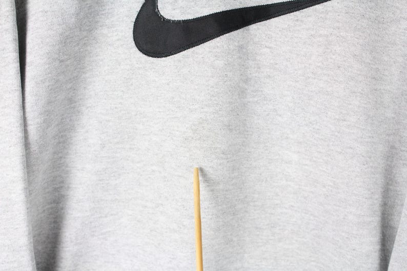 Puede incluir: Una sudadera gris con un logotipo Nike swoosh negro.