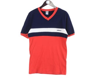 May include: A red, white, and navy blue short-sleeved t-shirt with a v-neck collar and the Adidas logo on the chest.