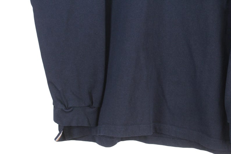 May include: Navy blue long-sleeve shirt. The shirt has a crew neck and a ribbed cuff. The bottom hem is straight. The fabric appears to be a soft, knit material. The shirt is a solid color.