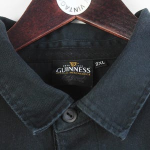 May include: Black polo shirt with a blue trim and a Guinness label that reads "Est. 1778 Dublin, Ireland, Guinness, Official Merchandise". The label also has a 2XL size tag.