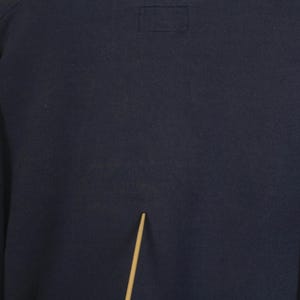 K&ouml;nnte beinhalten: Ein marineblaues Sweatshirt mit einem rechteckigen Aufn&auml;her in der N&auml;he des Halsausschnitts. Das Sweatshirt hat lange &Auml;rmel und ein schlichtes, klassisches Design, das sich f&uuml;r Freizeitkleidung eignet. Der Stoff scheint ein weiches, bequemes Material zu sein.