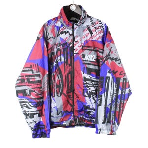 May include: A vintage Nike jacket with a colorful abstract print featuring red, blue, black, and white. The jacket has a zipper closure and a stand-up collar.