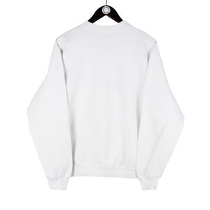 May include: A plain white sweatshirt with long sleeves, a crew neck, and ribbed cuffs and hem. The sweatshirt is hanging on a black hanger against a white background. The garment is a casual style.
