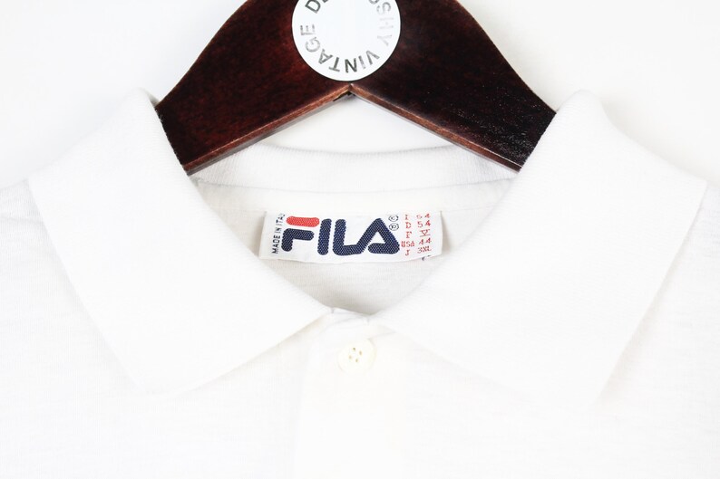 May include: A white ceramic mug with a black handle and the text "But First, Coffee" in a bold, black font. The mug is sitting on a wooden surface. The mug is approximately 4 inches tall.