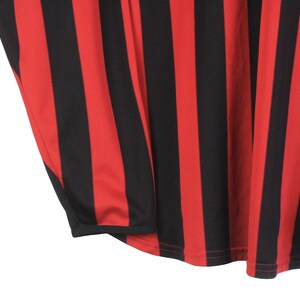 Puede incluir: Primer plano de una tela a rayas rojas y negras. Las rayas verticales se alternan en color, creando un patr&oacute;n audaz. La tela parece ser un material ligero, posiblemente para ropa.