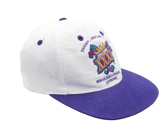 May include: White and purple baseball cap with the Super Bowl XXX logo. The cap has a white crown, a purple brim, and the text "SUNDAY, JANUARY" and "NEW ORLEANS-LOUISIANA SUPERDOME".