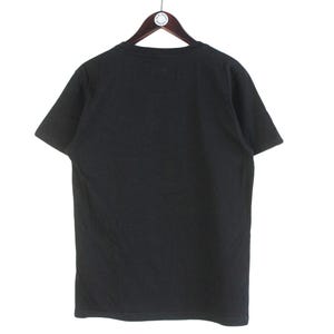 以下が含まれることがあります： 木製のハンガーに掛けられた、黒色の半袖Tシャツ。 シャツは無地で、クルーネックです。 背景は白です。