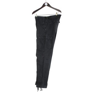 Puede incluir: Pantalones cargo negros colgados de una percha de madera. Los pantalones tienen m&uacute;ltiples bolsillos y cordones en los tobillos. La tela es oscura, posiblemente de mezclilla.