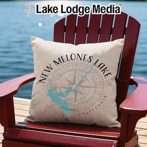 May include: A square off-white throw pillow featuring a graphic of a compass rose overlaid with a light blue map of New Melones Lake, California. The text "NEW MELONES LAKE" is printed in black in a circular arc above the compass design.