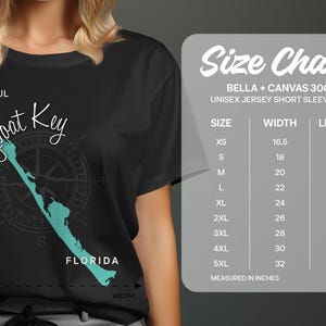 May include: Black unisex jersey short sleeve tee featuring a teal map of Longboat Key, Florida, with a compass design. The shirt includes the text "Longboat Key" and "Florida". A size chart is also displayed.