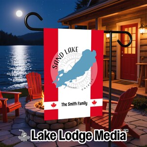 Peut inclure: Un drapeau de jardin vertical avec un motif à rayures rouges et blanches, une silhouette de carte bleu clair du lac Sand, Ontario, superposée à un graphique de rose des vents. Le texte indique Sand Lake, Ontario, et The Smith Family.