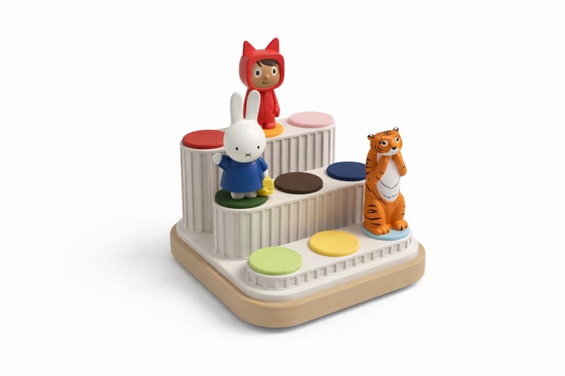 Puede incluir: Un juguete de varios niveles con plataformas circulares coloridas y figuras de un conejo, un tigre y una persona con un atuendo rojo. El juguete tiene una base beige y columnas blancas. Las figuras est&aacute;n colocadas en las plataformas.