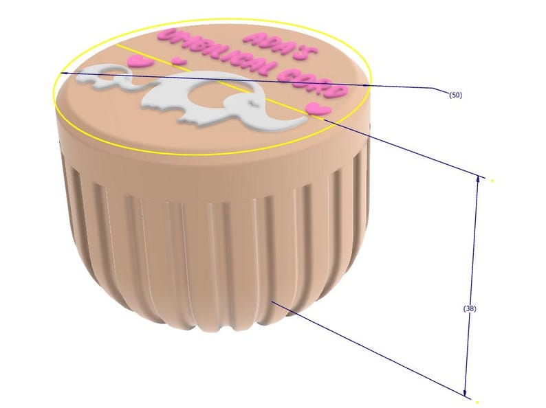 May include: A tan-colored container with a rounded bottom and vertical grooves. The top features the text "ADA'S UMBILICAL CORD" in pink, along with a white elephant design and pink hearts. The container is approximately 38 mm tall and 50 mm wide.