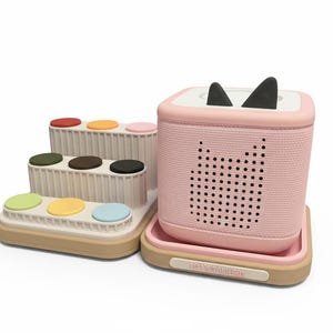 Puede incluir: Un juego de juguetes para ni&ntilde;os rosa y beige. El juego incluye un altavoz rosa con orejas de gato negras y un dise&ntilde;o de cara de gato perforada. Tambi&eacute;n hay una estructura de varios niveles con cojines circulares de colores. La base del altavoz tiene el texto "TONS TOYBOX".