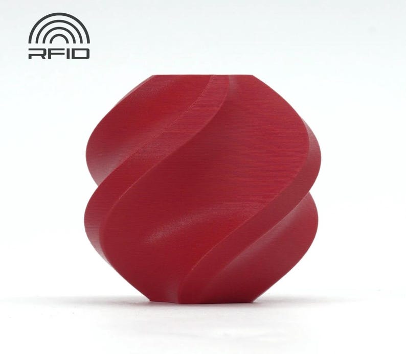 May include: A red, abstract sculpture with a twisted, symmetrical design. The object has a smooth, matte finish and is set against a white background. The sculpture's form is reminiscent of a stylized knot or a continuous ribbon.