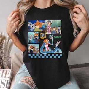 Może przedstawiać: Czarna koszulka z kolorową grafiką postaci z filmu animowanego "Zwierzogr&oacute;d". Projekt zawiera wizerunki Judy Hopps, Nicka Wilde'a i innych postaci. Widoczne jest r&oacute;wnież słowo "Zwierzogr&oacute;d".