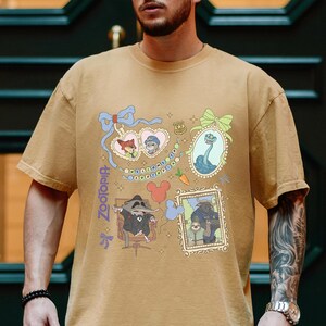 Puede incluir: Camiseta de manga corta color canela con un dise&ntilde;o gr&aacute;fico colorido de la pel&iacute;cula Zootopia. El dise&ntilde;o incluye retratos de personajes enmarcados, una zanahoria y la palabra "Zootopia". La camiseta tiene cuello redondo y un corte holgado.