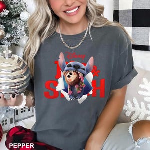 Puede incluir: Camiseta gris oscuro con el personaje de Disney Stitch rompiendo un efecto de papel rasgado. La camiseta tiene las palabras "Lilo & Stitch" en rojo y el logotipo de Disney. La camiseta es de estilo casual y c&oacute;modo.