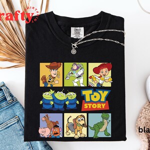 Pu&ograve; includere: Maglietta nera a tema Toy Story. La maglietta presenta un collage di personaggi del film, tra cui Woody, Buzz Lightyear, Jessie e gli alieni. Il testo "Toy Story" &egrave; stampato in lettere gialle sulla maglietta.