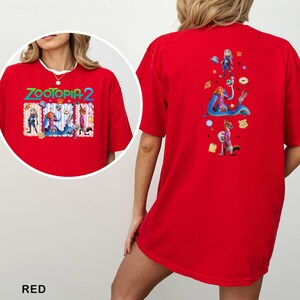 May include: Red t-shirt featuring the text "ZOOTOPIA 2" with cartoon characters on the front and back. The front design includes characters in a rectangular frame. The back design features additional characters and icons.