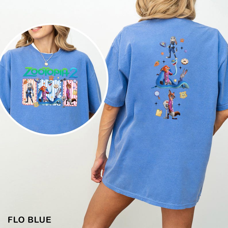 May include: Flo blue t-shirt featuring the text "ZOOTOPIA 2" with cartoon characters. The back of the shirt has a vertical design with more cartoon characters and icons. The shirt is a comfortable, oversized fit.