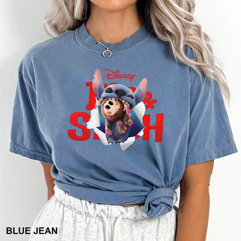 Puede incluir: Una camiseta azul vaquera con un gr&aacute;fico de Stitch de Lilo & Stitch de Disney. El gr&aacute;fico muestra a Stitch rompiendo un agujero con un mono marr&oacute;n. Tambi&eacute;n se ve el texto "Disney" y "Lilo & Stitch".