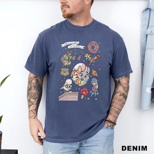 Puede incluir: Camiseta azul marino con personajes de dibujos animados y el texto "You can be anything you want to be." El dise&ntilde;o incluye una rosquilla, una placa de polic&iacute;a y varios personajes de animales. La camiseta es de material suave.
