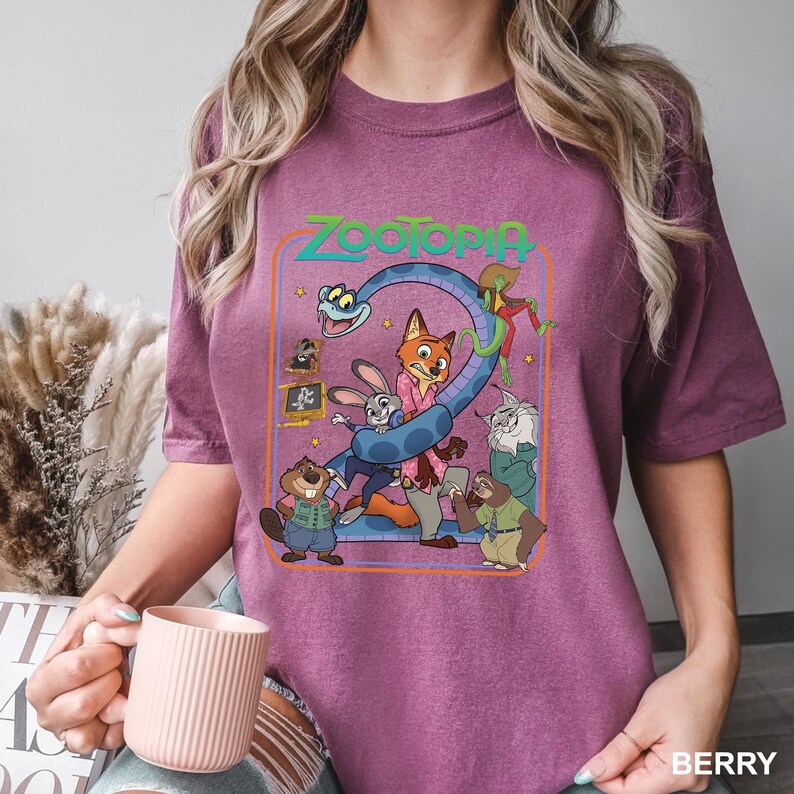 Puede incluir: Camiseta de color bayas con un gr&aacute;fico colorido de la pel&iacute;cula animada "Zootopia". El dise&ntilde;o incluye el t&iacute;tulo de la pel&iacute;cula y varios personajes, como un zorro, un conejo y un perezoso. La camiseta es de material suave.