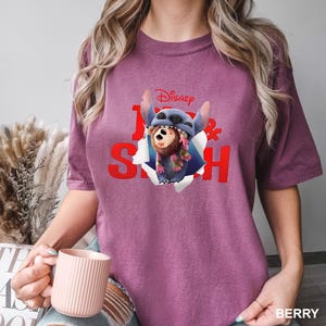 Puede incluir: Camiseta color bayas con un gr&aacute;fico de Stitch de Lilo & Stitch de Disney. El dise&ntilde;o muestra a Stitch saliendo de un efecto de papel rasgado, con las palabras "Lilo & Stitch" en rojo. La camiseta es de estilo casual y manga corta.