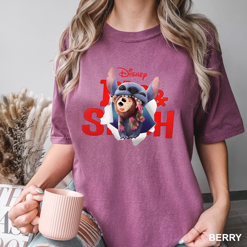 Puede incluir: Camiseta color bayas con un gr&aacute;fico de Stitch de Lilo & Stitch de Disney. El dise&ntilde;o muestra a Stitch saliendo de un efecto de papel rasgado, con las palabras "Lilo & Stitch" en rojo. La camiseta es de estilo casual y manga corta.