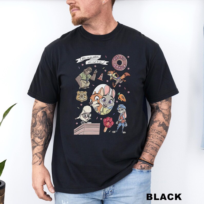 Puede incluir: Camiseta negra con personajes de dibujos animados y el texto "You can be whatever you wish to be" y "THE BIG DONUT". El dise&ntilde;o incluye una rosquilla, una zanahoria y varios personajes.