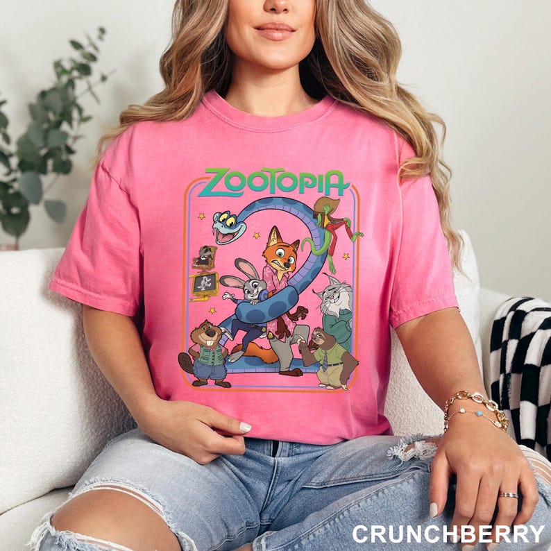 Puede incluir: Una camiseta rosa con un dise&ntilde;o gr&aacute;fico colorido de la pel&iacute;cula animada Zootopia. El dise&ntilde;o incluye personajes como Judy Hopps y Nick Wilde, con el t&iacute;tulo de la pel&iacute;cula en la parte superior. La camiseta es de cuello redondo.