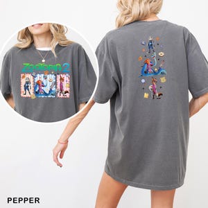 May include: Pepper-colored t-shirt featuring the text "Zootopia 2" with cartoon characters on the front. The back of the shirt displays a vertical graphic of characters and objects from the movie. The shirt has short sleeves and a relaxed fit.