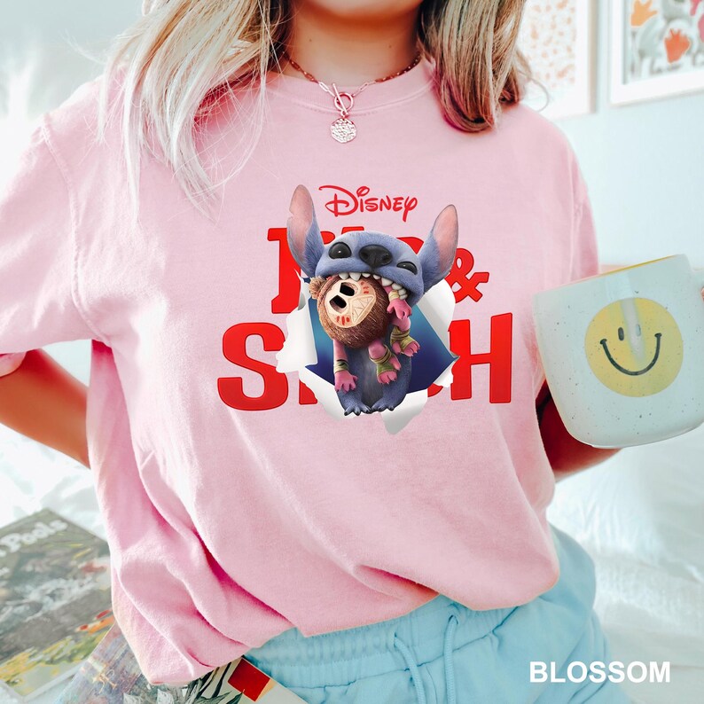 Puede incluir: Camiseta rosa claro con un dise&ntilde;o de Disney "Lilo & Stitch". El dise&ntilde;o muestra a Stitch sosteniendo un personaje. Se sostiene una taza blanca con una carita sonriente amarilla. La palabra "BLOSSOM" est&aacute; en la parte inferior.