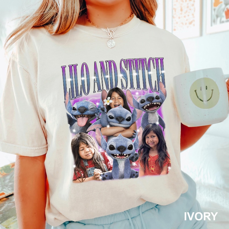 May include: Ivory-colored t-shirt featuring a graphic of the characters Lilo and Stitch. The design includes the text "LILO AND STITCH" in a purple and blue font, along with images of the characters and children. A white mug with a smiley face is also visible.