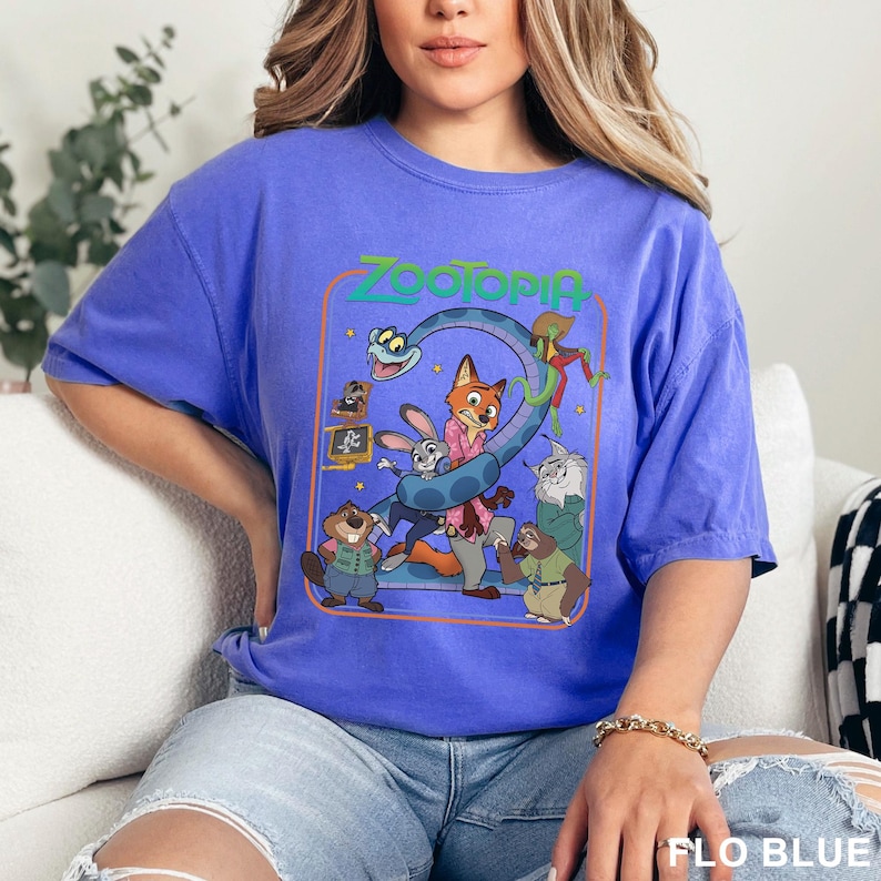 Puede incluir: Una camiseta azul con un gr&aacute;fico colorido de la pel&iacute;cula "Zootopia". El dise&ntilde;o presenta personajes como Judy Hopps y Nick Wilde, junto con el t&iacute;tulo de la pel&iacute;cula en verde. La camiseta es de estilo casual y c&oacute;modo.