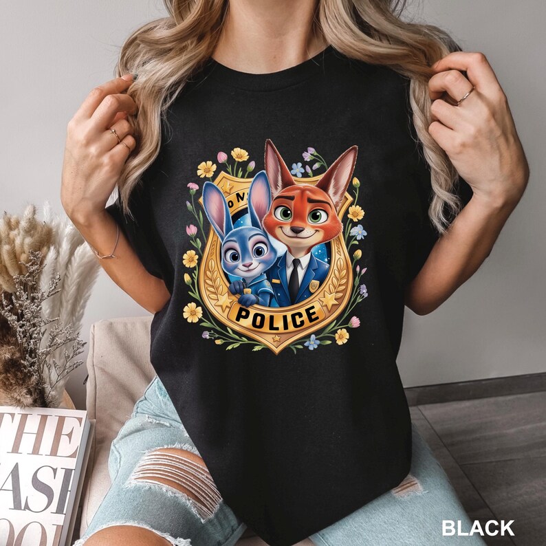 May include: Black t-shirt featuring a cartoon image of a bunny and fox in police uniforms, surrounded by flowers and a gold badge that says "POLICE". The text "BLACK" is at the bottom right.