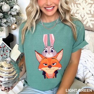 Puede incluir: Camiseta verde claro con un dise&ntilde;o de dibujos animados de un zorro y un conejo. El zorro es naranja, el conejo es gris. El texto "LIGHT GREEN" est&aacute; impreso en la parte inferior de la camiseta.