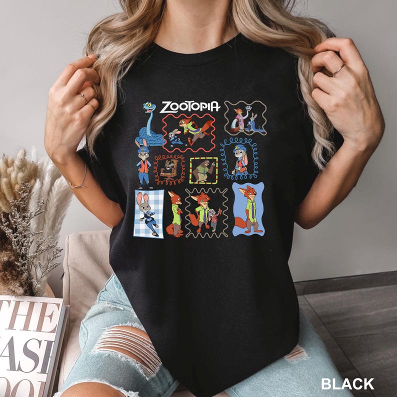 May include: Black t-shirt featuring a colorful graphic of characters from the animated film "Zootopia." The design includes multiple framed images of the characters, with the film's title at the top. The word "BLACK" is printed at the bottom.